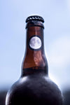 A moon sticker on the neck of a bottle of Skyshift beer. Part of the label artwork illustrated by Arsenal Handicraft.